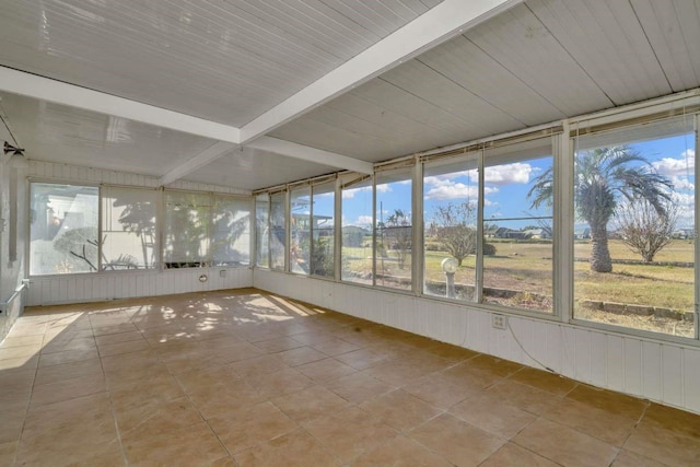 unfurnished sunroom featuring beam ceiling