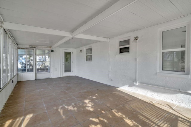 unfurnished sunroom with beam ceiling