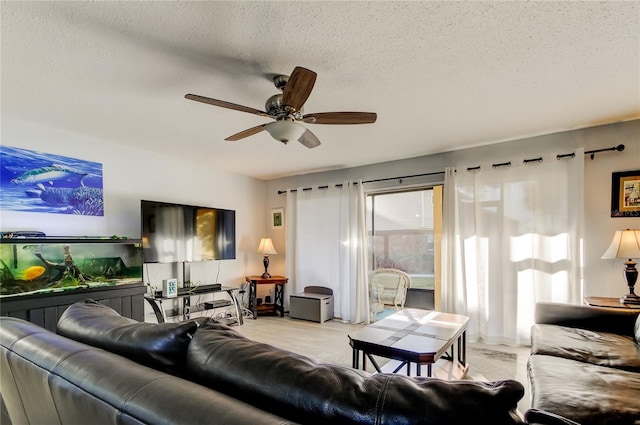 living room featuring ceiling fan and a textured ceiling