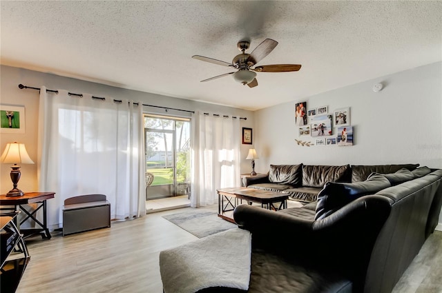 living room featuring ceiling fan, a textured ceiling, and light hardwood / wood-style floors