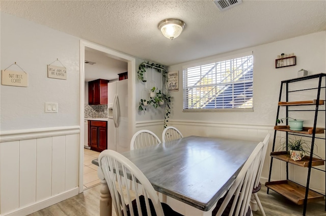 dining space featuring light hardwood / wood-style floors and a textured ceiling