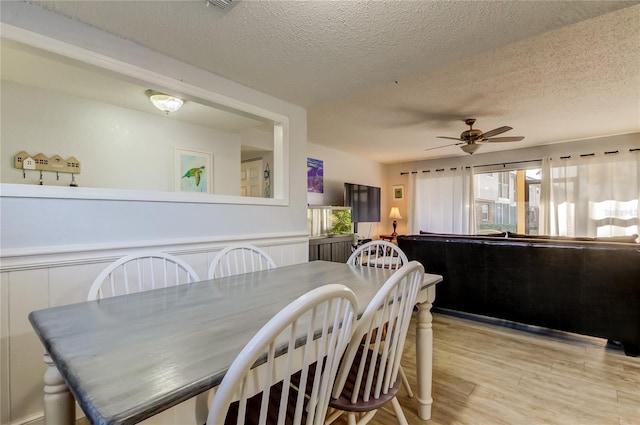 dining area with ceiling fan, light hardwood / wood-style floors, and a textured ceiling