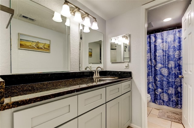 bathroom with tile patterned flooring, vanity, a textured ceiling, toilet, and walk in shower