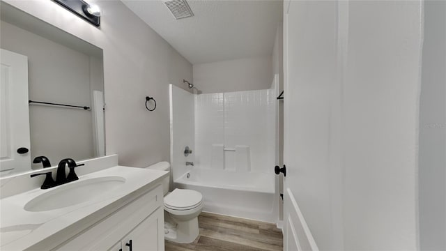 full bathroom featuring vanity, wood-type flooring, a textured ceiling, bathtub / shower combination, and toilet