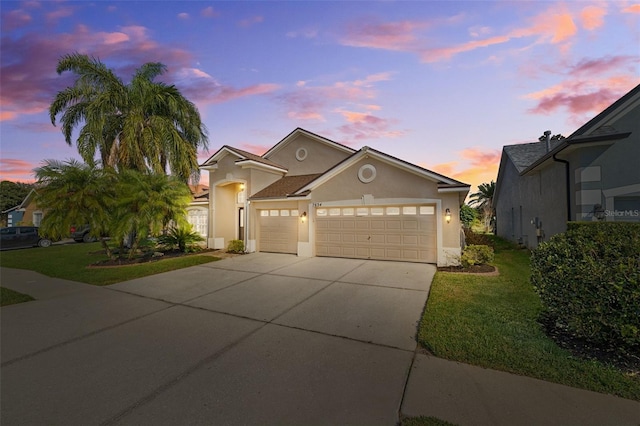 view of front of home featuring a garage, driveway, a front yard, and stucco siding