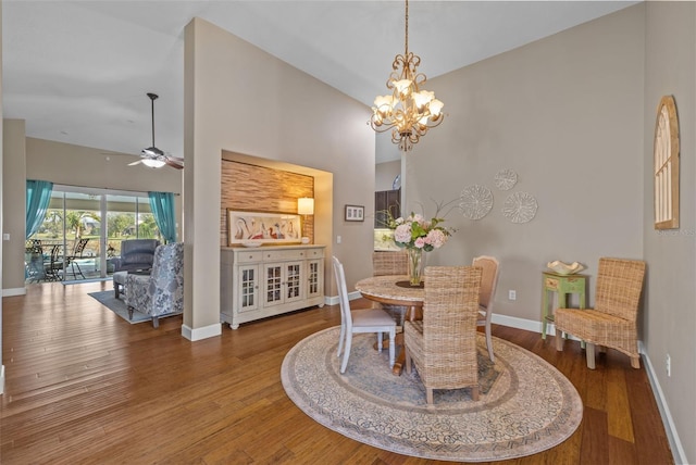 dining space featuring hardwood / wood-style flooring, ceiling fan with notable chandelier, and high vaulted ceiling