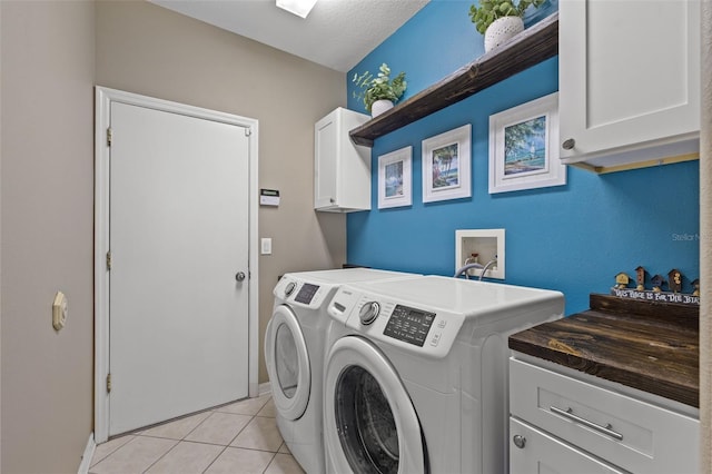 laundry room featuring cabinets, light tile patterned floors, and washer and clothes dryer