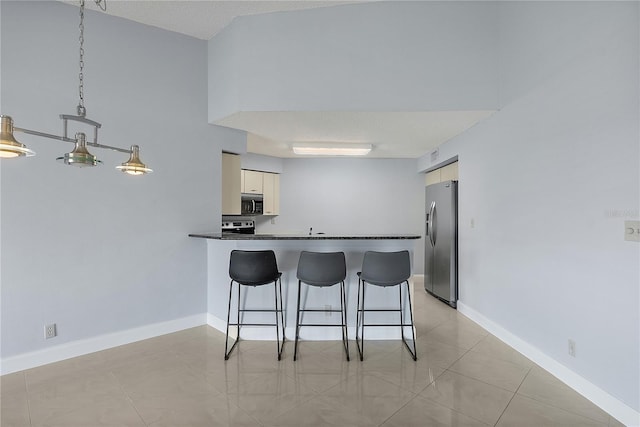 kitchen featuring a kitchen bar, decorative light fixtures, light tile patterned floors, kitchen peninsula, and stainless steel appliances