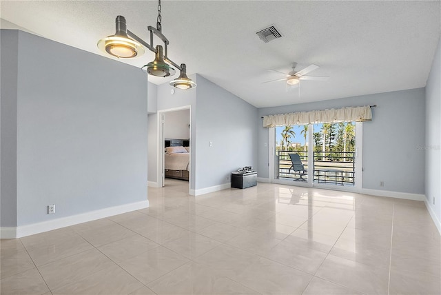 tiled spare room with ceiling fan, vaulted ceiling, and a textured ceiling