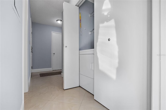 hallway with washer / dryer, a textured ceiling, and light tile patterned floors