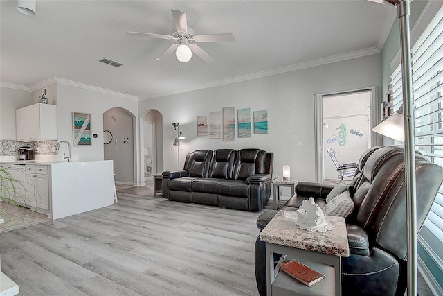 living room with crown molding, ceiling fan, sink, and light wood-type flooring