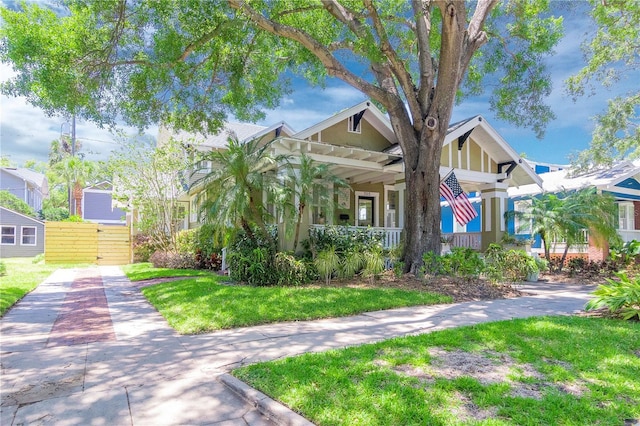 view of front of house featuring a porch, a front lawn, and fence