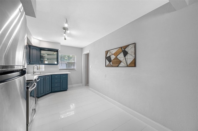 kitchen with blue cabinetry, rail lighting, sink, a textured ceiling, and stainless steel appliances