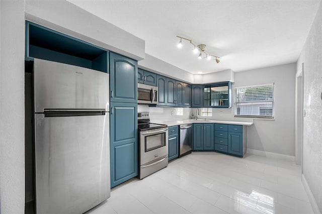 kitchen with blue cabinetry, stainless steel appliances, sink, and a textured ceiling