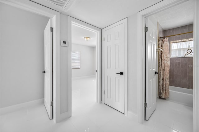 corridor with light tile patterned flooring and a wealth of natural light