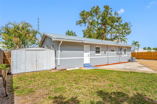 rear view of house with central AC unit, a yard, a patio, and a storage unit