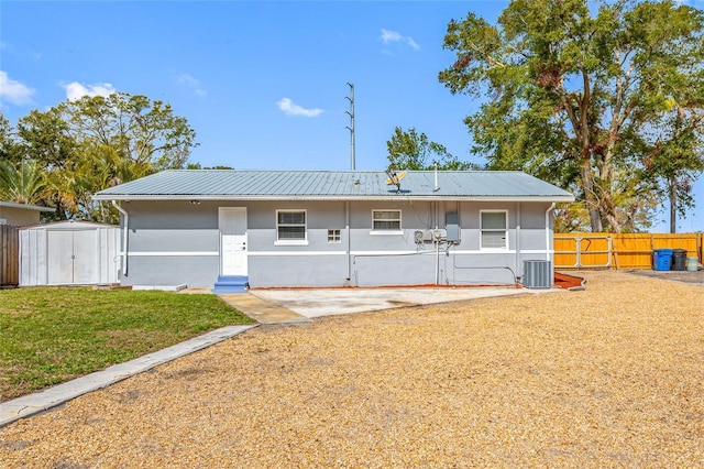 back of house featuring central AC, a lawn, a shed, and a patio area