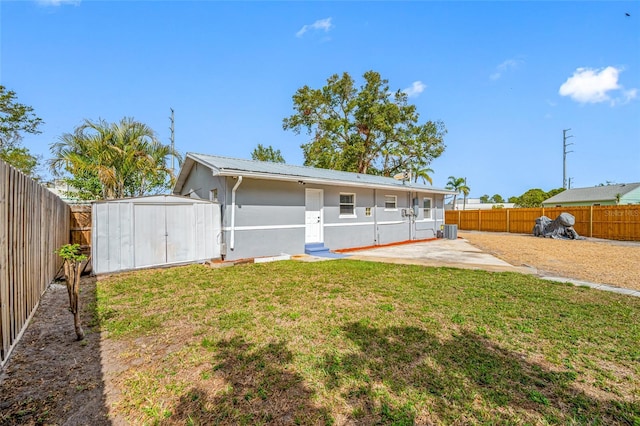 rear view of property with a storage shed, central AC, a patio area, and a lawn