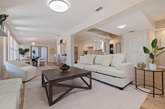 living room with a notable chandelier and light hardwood / wood-style floors