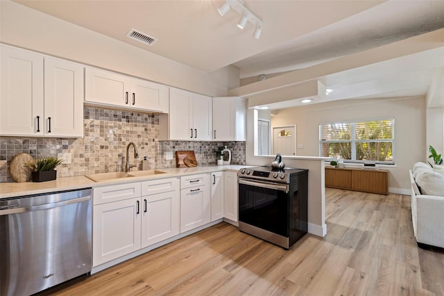 kitchen featuring sink, backsplash, white cabinetry, and stainless steel appliances