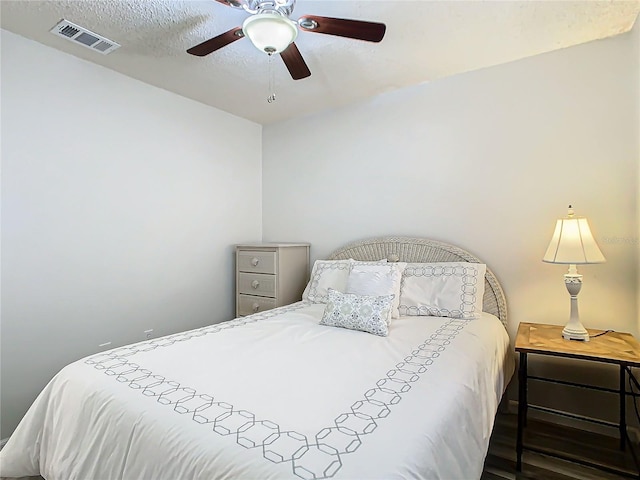 bedroom featuring ceiling fan, dark hardwood / wood-style floors, and a textured ceiling