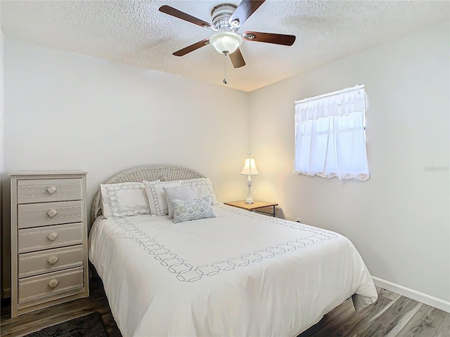 bedroom featuring dark wood-type flooring, ceiling fan, and a textured ceiling