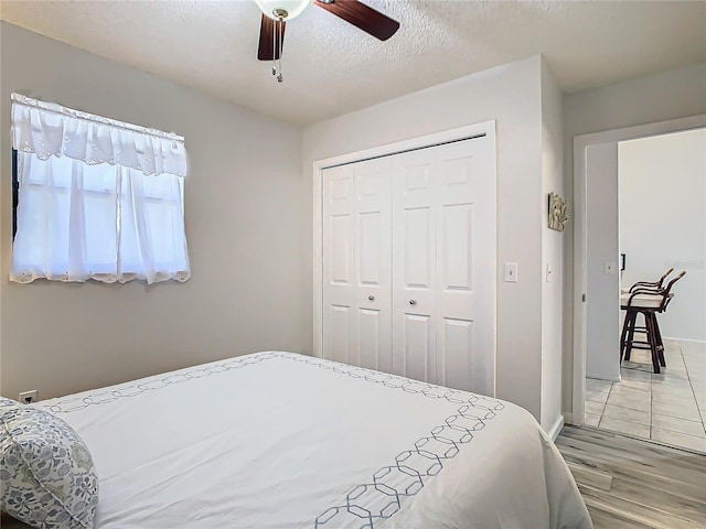 bedroom with ceiling fan, a closet, wood-type flooring, and a textured ceiling