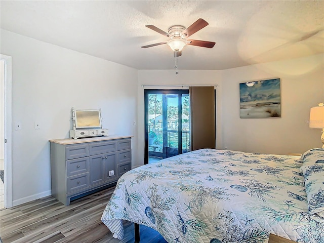 bedroom featuring hardwood / wood-style flooring, a textured ceiling, access to exterior, and ceiling fan