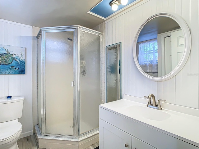 bathroom featuring a shower with door, vanity, and toilet