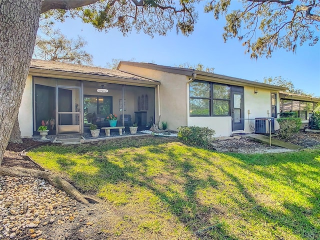 rear view of property featuring central AC, a lawn, and a sunroom