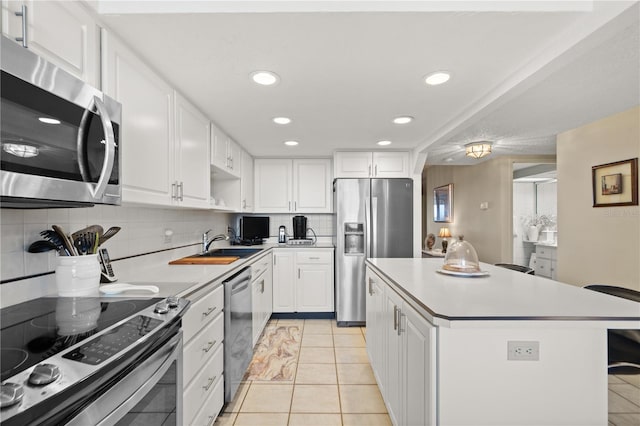 kitchen with light tile patterned floors, stainless steel appliances, a center island, white cabinets, and decorative backsplash