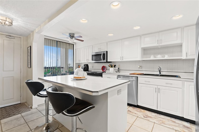 kitchen with white cabinetry, appliances with stainless steel finishes, sink, and a kitchen island