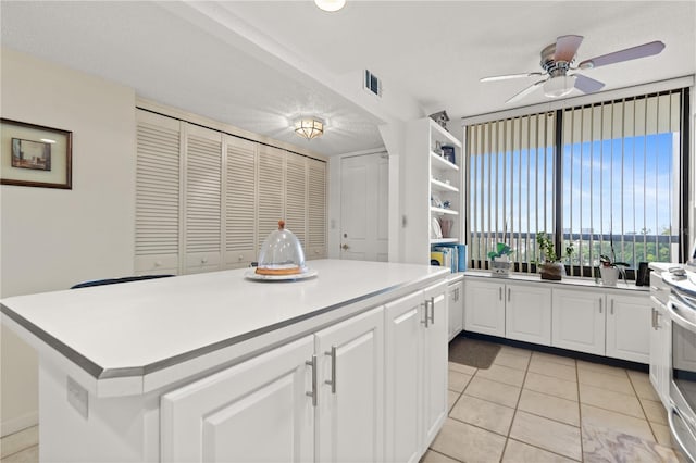 kitchen featuring white cabinetry, a center island, light tile patterned floors, ceiling fan, and a textured ceiling