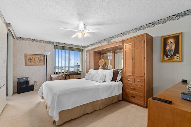 carpeted bedroom with ceiling fan and a textured ceiling