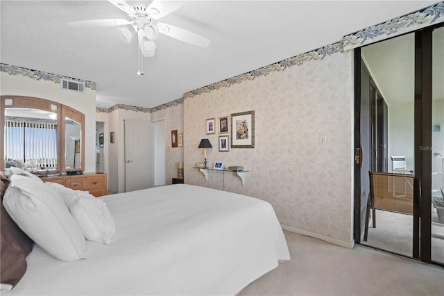 bedroom featuring ceiling fan, light colored carpet, and a textured ceiling