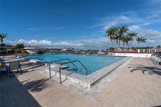 view of swimming pool featuring a patio area and a water view