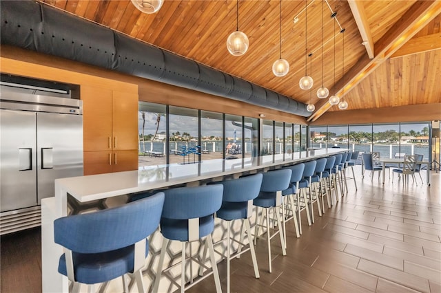 kitchen featuring a water view, wood ceiling, plenty of natural light, and hanging light fixtures