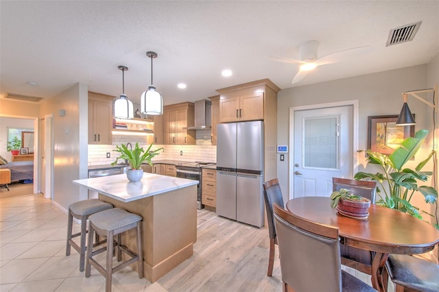 kitchen with stainless steel appliances, a kitchen island, visible vents, wall chimney exhaust hood, and tasteful backsplash