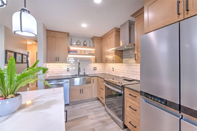 kitchen featuring decorative backsplash, dark stone counters, wall chimney exhaust hood, appliances with stainless steel finishes, and a sink