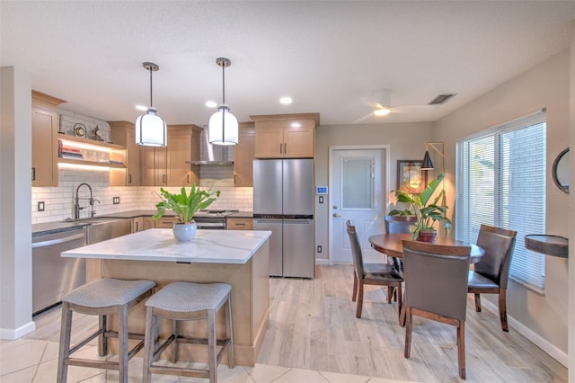 kitchen with visible vents, decorative backsplash, appliances with stainless steel finishes, a center island, and pendant lighting