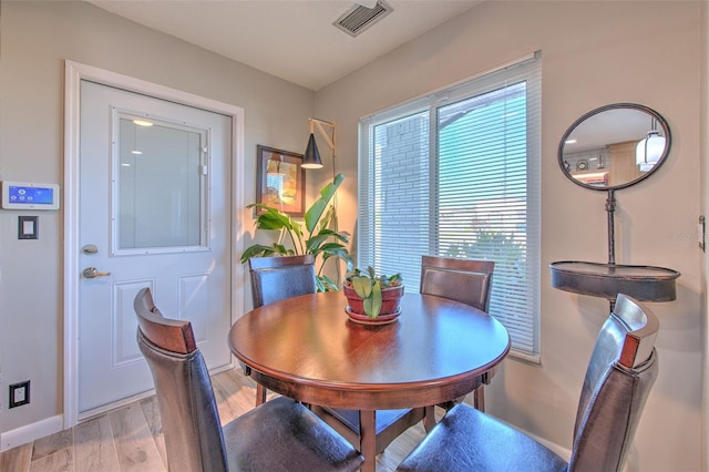 dining space with baseboards, visible vents, and light wood finished floors