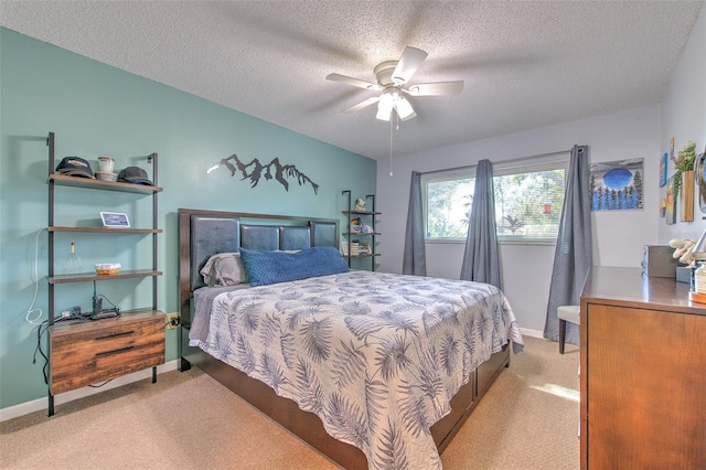 bedroom with ceiling fan, baseboards, a textured ceiling, and light colored carpet