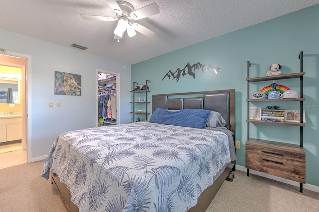 carpeted bedroom with a closet, visible vents, a spacious closet, a textured ceiling, and a sink