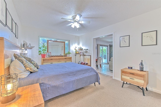 bedroom featuring light carpet, a ceiling fan, baseboards, and a textured ceiling