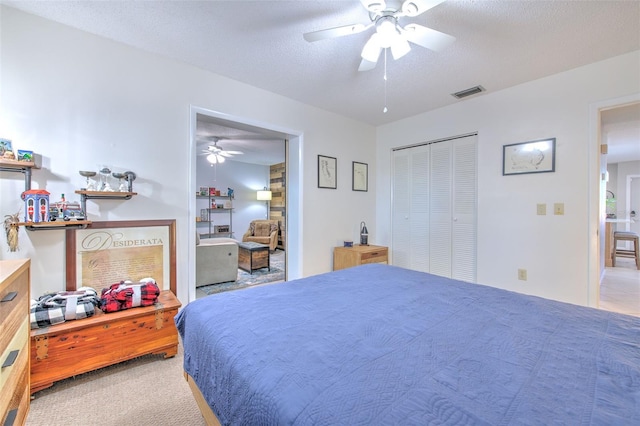 carpeted bedroom featuring a closet, visible vents, ceiling fan, and a textured ceiling