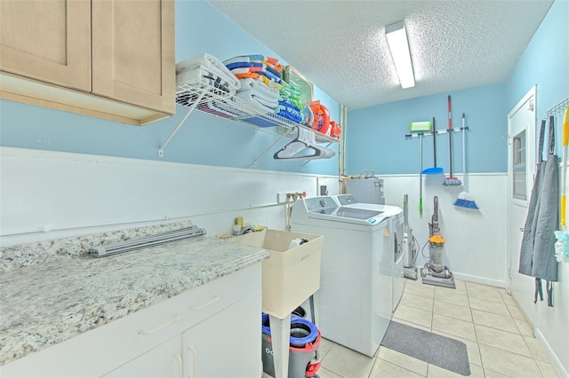 laundry room featuring cabinet space, light tile patterned floors, separate washer and dryer, and a textured ceiling