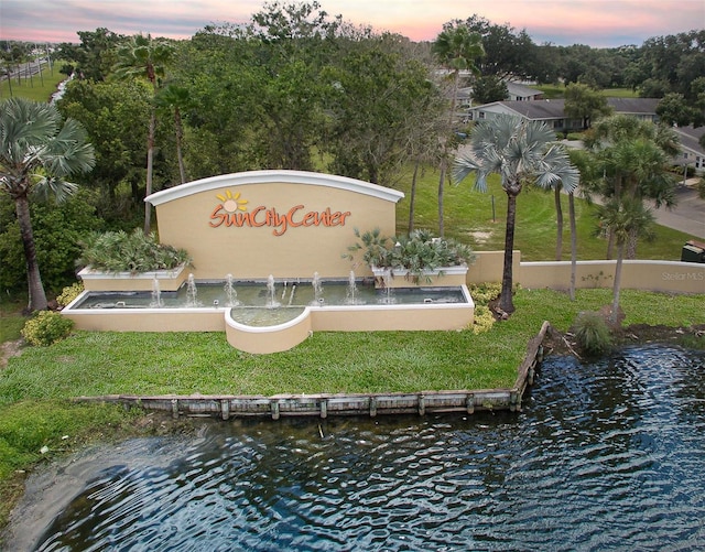 community / neighborhood sign featuring a water view and a yard