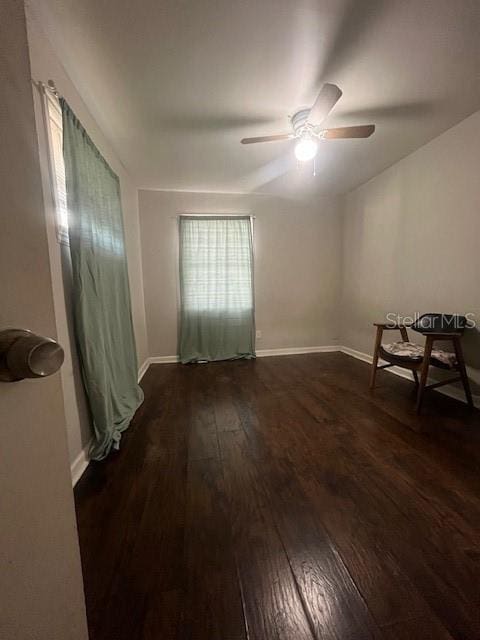 unfurnished room featuring dark wood-style floors, baseboards, and a ceiling fan