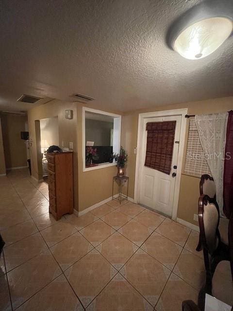 foyer with visible vents, light tile patterned flooring, a textured ceiling, and baseboards