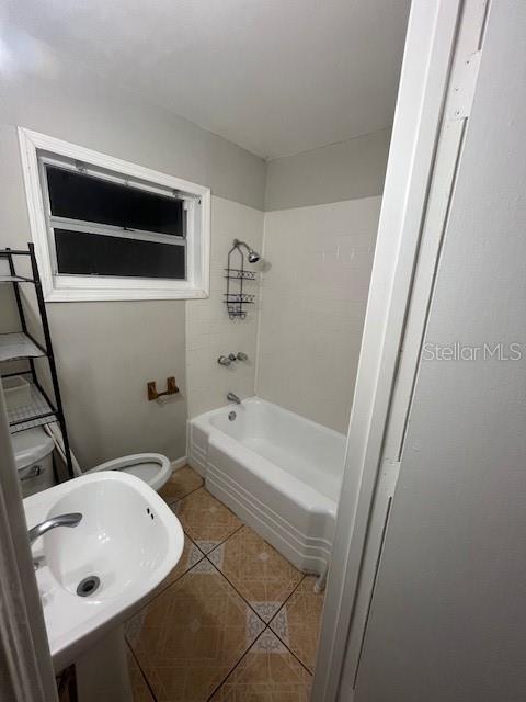 full bath with toilet, a sink, and tile patterned floors